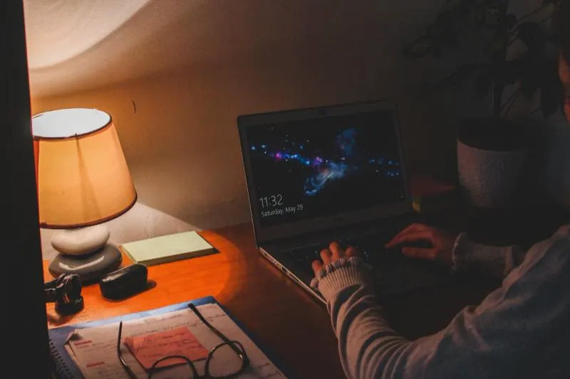 Laptop és asztali lámpa fénye késő este