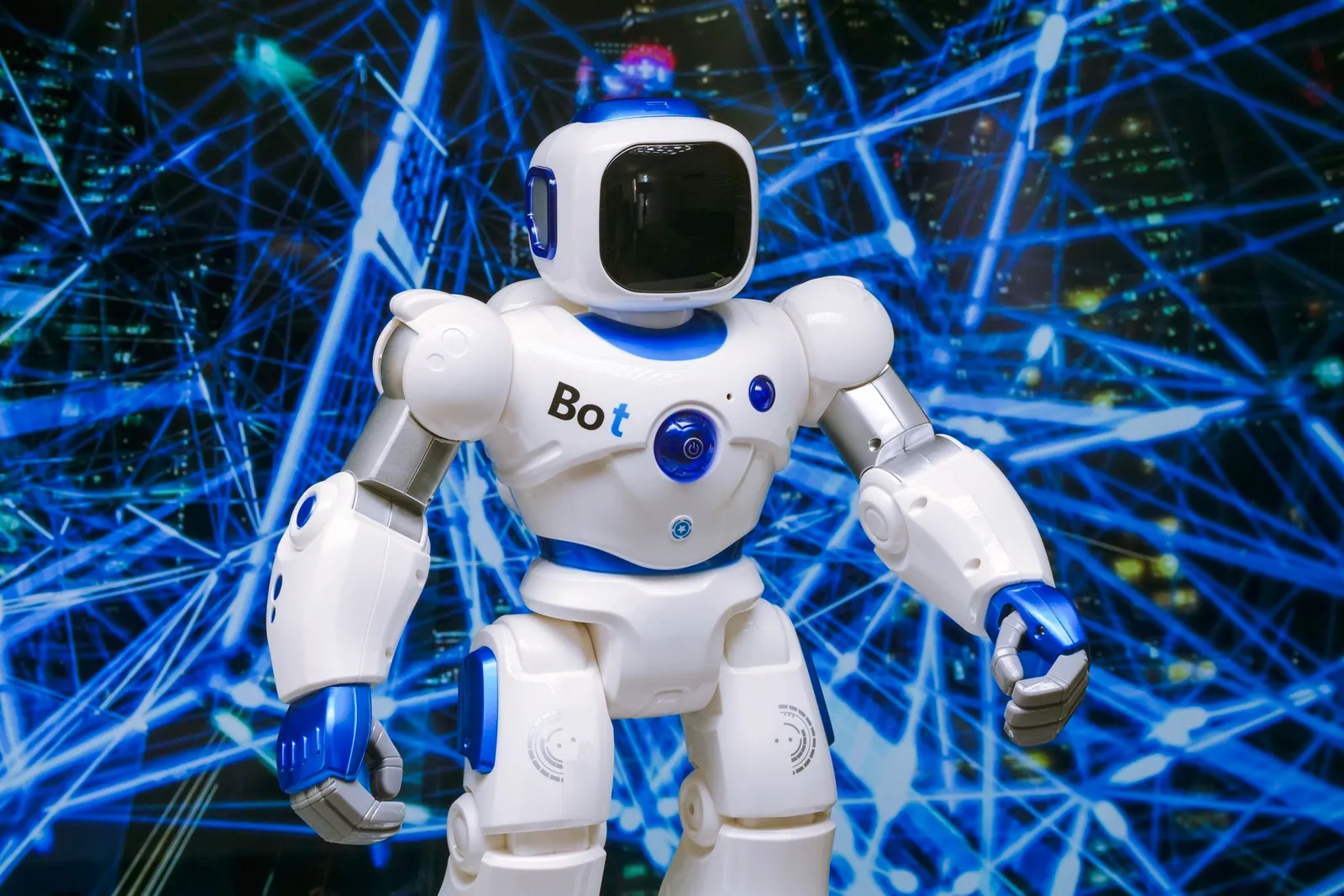 Fehér-kék játékrobot Bot felirattal, kék fényhálózat előtt